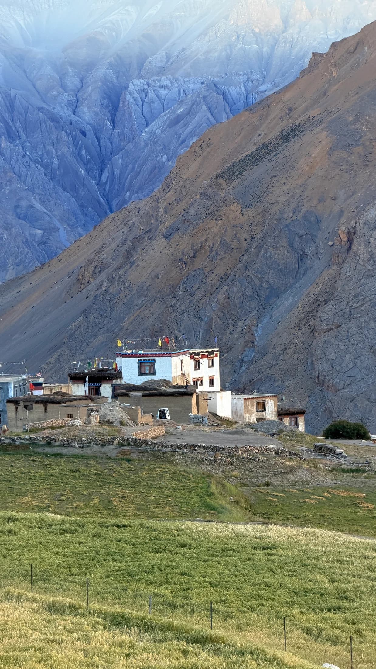 Village houses and green fields beneath steep mountains